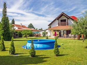 Una casa de dos pisos con un amplio patio trasero, una piscina y un porche cubierto.