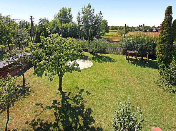 Un jardín bien cuidado con varios árboles, césped y una valla de madera.