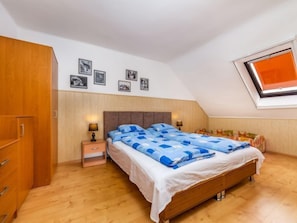 Un dormitorio con cama, armario de madera, mesitas de noche y tragaluz.