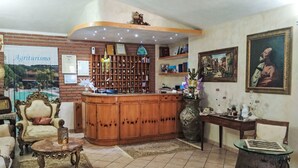 Een knus ogende lobby met een houten receptiebalie, een boekenplank en een zithoek met een kamerbreed tapijt.