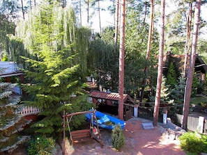 A rustic cabin surrounded by tall trees and a swing set. - Mielno 2 by Interhome (Grunwald)