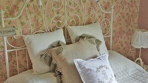 Un lit avec une tête de lit à motifs floraux et plusieurs oreillers.