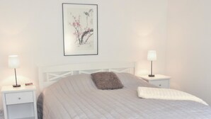 A bedroom with a bed, two bedside tables, a nightstand, a framed picture on the wall, and a fluffy pillow. - Villa paasirinne b by Interhome (Toivakka)