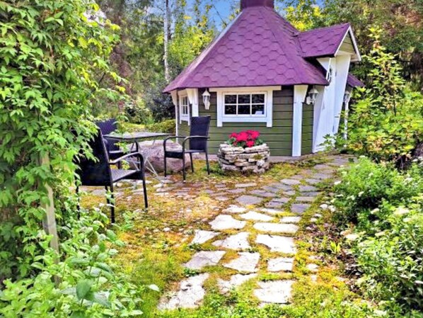 A small house with a stone pathway leading to a seating area with chairs. - Villa paasirinne b by Interhome (Toivakka)