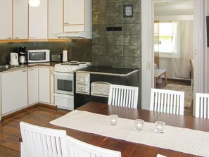 Una cocina con armarios blancos, un microondas, una estufa y una mesa de comedor con sillas.