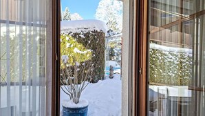 A doorway leading to a snowy outdoor area with a potted plant and a snow-covered wall. - Chalet am Reeti by Interhome (Grindelwald)