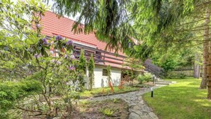 A stone pathway leading to a house with a red roof, surrounded by lush greenery and trees. - Vacation home Hatale by Interhome (Rzyki)