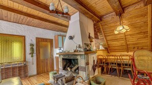A cozy cabin interior with a stone fireplace, wooden furniture, and a high ceiling with exposed beams. - Vacation home Hatale by Interhome (Rzyki)