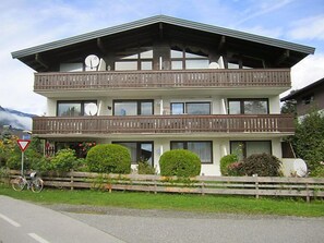 A two-story building with balconies, a wooden fence, and a mountain in the background.