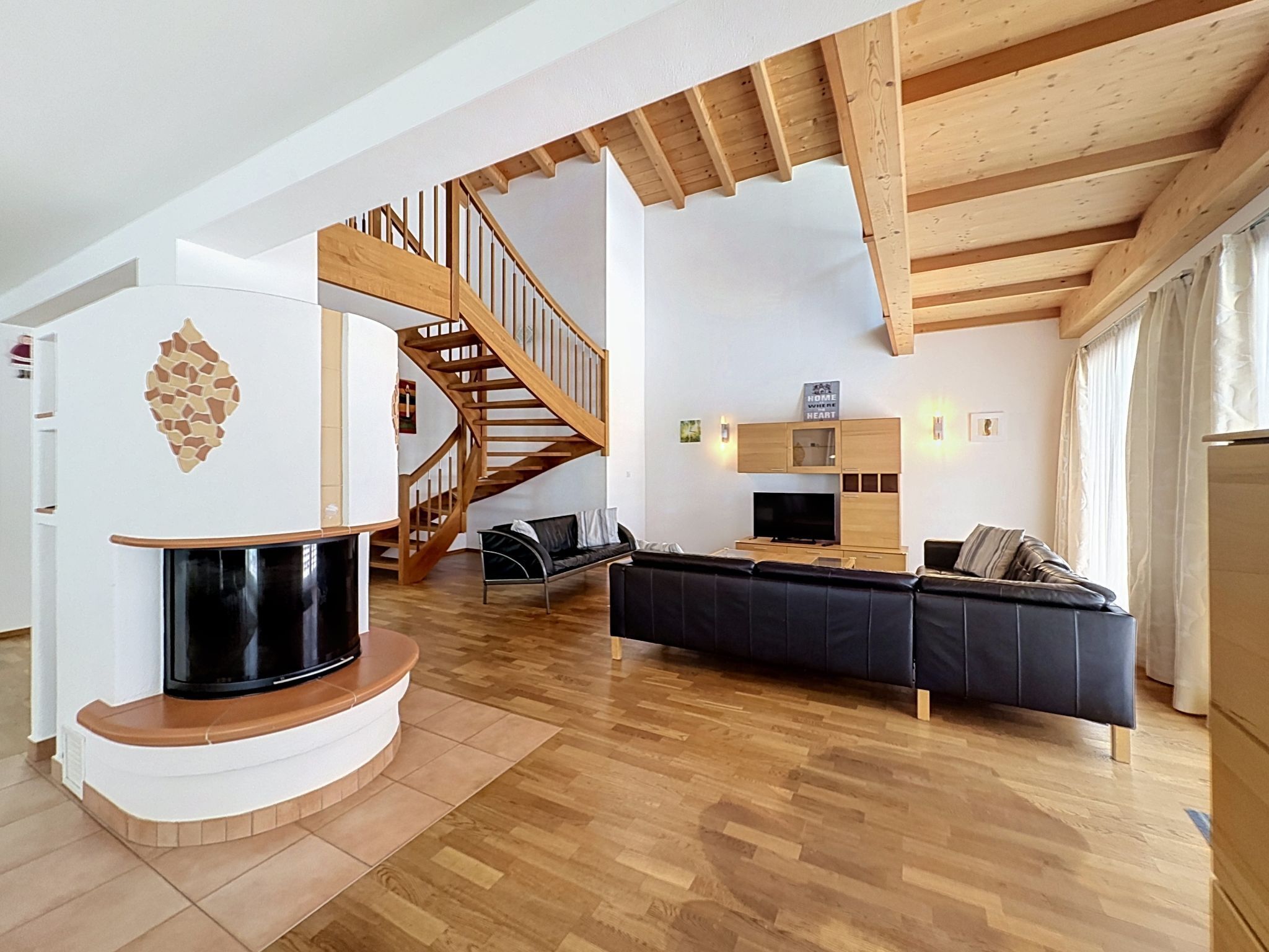Ein modernes Wohnzimmer mit Kamin, Holztreppe und einer Couch.