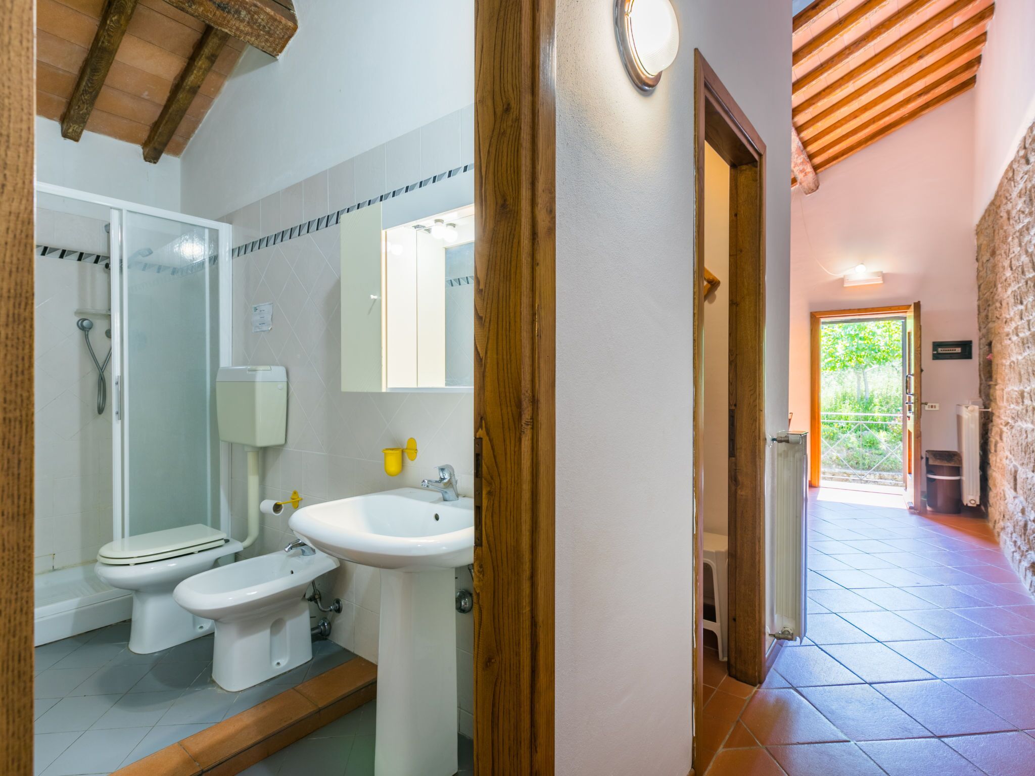 Een badkamer met een douche, twee toiletten, een wastafel en een spiegel.
