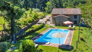 A stone building with a tiled roof, surrounded by a swimming pool and lush greenery. - Certina 4 by Interhome (Pontassieve)