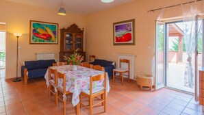 Un comedor con una mesa dispuesta para cuatro personas, un armario, un sofá y una silla.