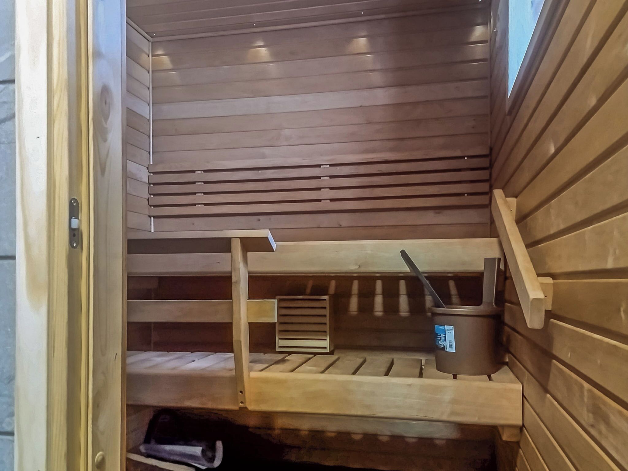 Una sauna con bancos de madera y un cubo y una cuchara.