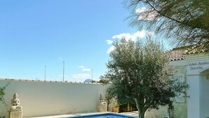 Une piscine avec un petit arbre et un mur blanc sur lequel est fixée une plaque avec un nom.