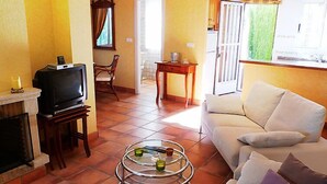 Un salon avec une cheminée, un téléviseur, un canapé et une table basse en verre.