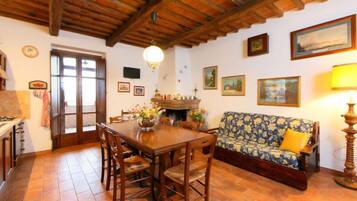 Un soggiorno accogliente con un tavolo da pranzo in legno, sedie, un divano e un camino.