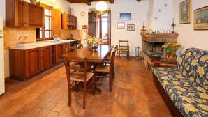 Ein gemütliches Wohnzimmer mit einem Holzesstisch, Stühlen, einer Couch und einem Kamin.