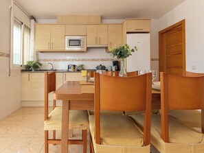 Une cuisine moderne avec des meubles en bois, un four à micro-ondes et un coin repas comprenant une table et des chaises en bois.