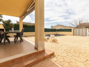 Un patio cubierto con mesa y sillas, una piscina y un patio con baldosas de piedra.