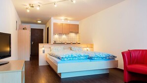 Ein modernes Schlafzimmer mit einem Bett, einem roten Sessel und einem Fernseher.
