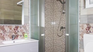 Kylpyhuone, jossa on lasiseinällä varustettu suihku, pesuallas ja wc.