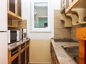 Een koelkast, een microgolfoven, kookgerei, borden en bestek