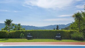 A swimming pool with two lounge chairs and a hedge in the foreground, with a mountainous landscape in the background. - Casa di Nena by Interhome (Camaiore)