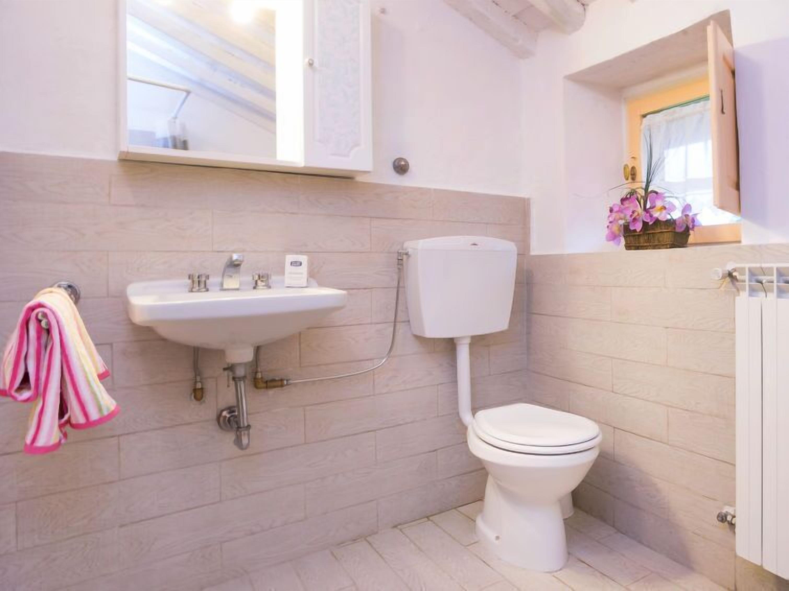 Un baño con lavamanos blanco, inodoro y paredes con azulejos.