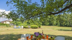 An outdoor dining table set up in a garden with a view of a house and a swimming pool in the background. - San Bernardino by Interhome (Barga)