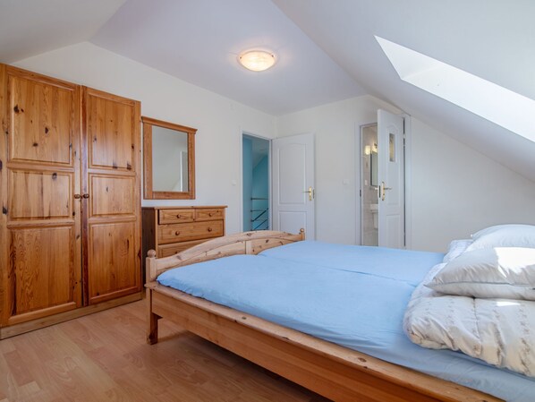 Une chambre à coucher avec un lit en bois, une commode, un miroir et une armoire.