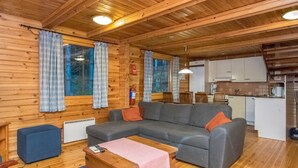 A cozy cabin interior with a wooden interior, a sofa, a small table, and a kitchenette. - Mustikka by Interhome (Hämeenlinna)