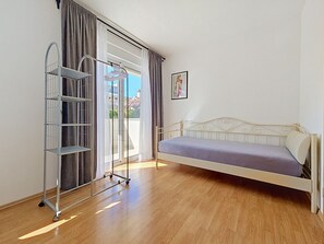 A bedroom with a bed, a metal wardrobe, and a window with curtains. - Apartment Anđa by Interhome (Trogir/Slatine)