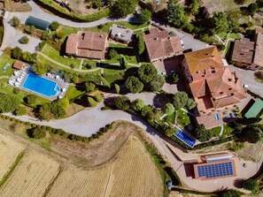 Luchtbeeld van een woonwijk met meerdere huizen, een zwembad en zonnepanelen.