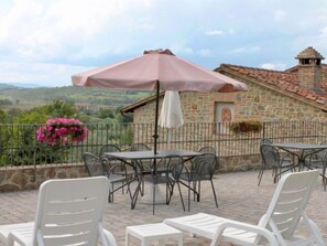 Relax in the serene outdoor patio surrounded by lush greenery and a scenic view of the surrounding landscape.
