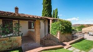 Une maison en pierre avec un toit en tuiles, une entrée en briques et un petit porche.