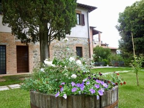 Situated in a lush, landscaped environment, this traditional property features a well-maintained garden with a variety of flowering plants and a planter.