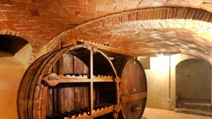 Ein großer Holzbottich mit Gitterstruktur im Inneren, möglicherweise ein Weinfass oder Bierfass, in einem Keller mit Backsteinwänden.