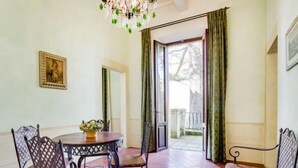 Ein Essbereich mit einem runden Tisch, Stühlen und einer Bank. Über dem Tisch hängt eine Chandelüster und an der Wand hängt ein gerahmtes Bild.