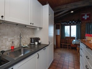 A kitchen with white cabinets, a black countertop, and a tiled backsplash.