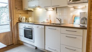 A modern kitchen with white cabinetry, a built-in oven, a microwave, and a coffee maker.