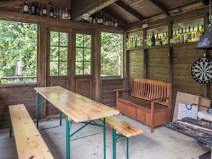 A rustic wooden room with a wooden table, bench, and a dartboard.
