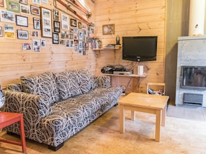 Een gezellige woonkamer met een gestreept bankje, een televisie en een open haard.
