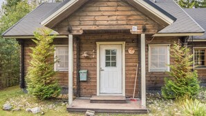 A wooden cabin with a front porch, a mailbox, and a door.