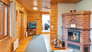 A wooden interior with a fireplace, a television, and a hallway leading to another room.