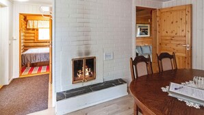 A log cabin interior with a fireplace, a dining table, and a cozy bed area.