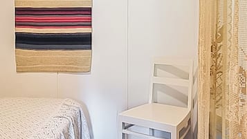 Makuuhuoneessa on sänky, tuoli, pieni pöytä ja seinälle ripustettu seinävaate.