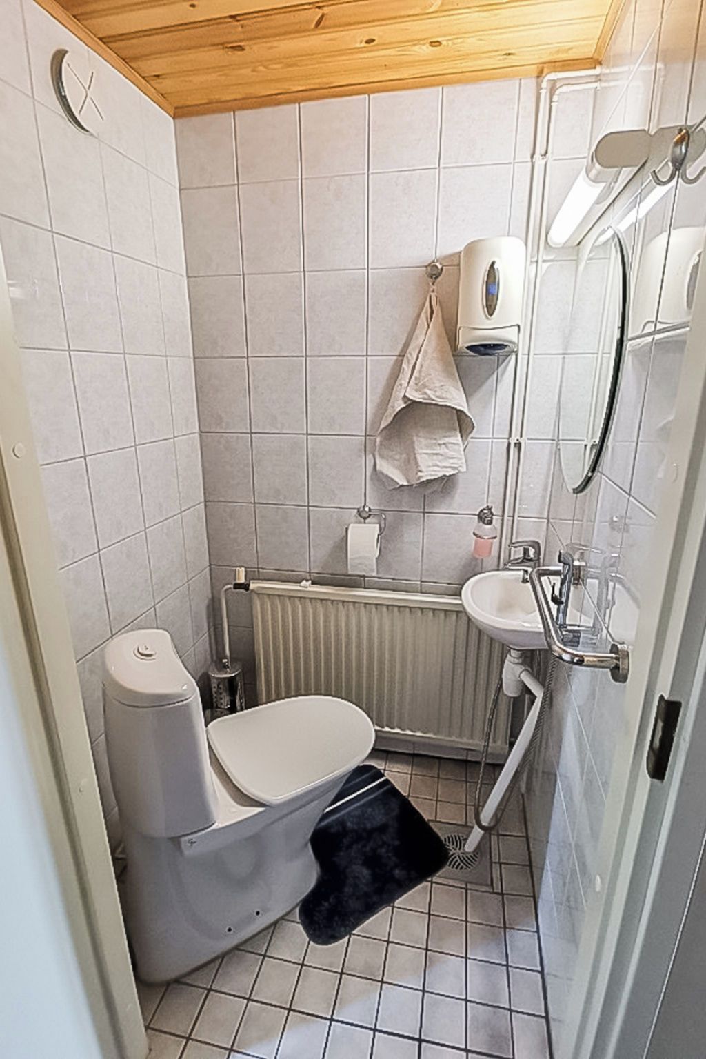 Ein kleines Badezimmer mit Toilette, Waschbecken, Handtuchhalter und Dusche.