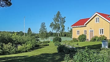 Keltainen rakennus, jossa on punainen katto, ja sen ympärillä on vehreää kasvillisuutta ja kirkas taivas.