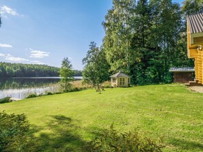 Une propriété au bord du lac, comprenant un petit chalet en bois, une pelouse verdoyante et une jetée s’avançant dans l’eau.